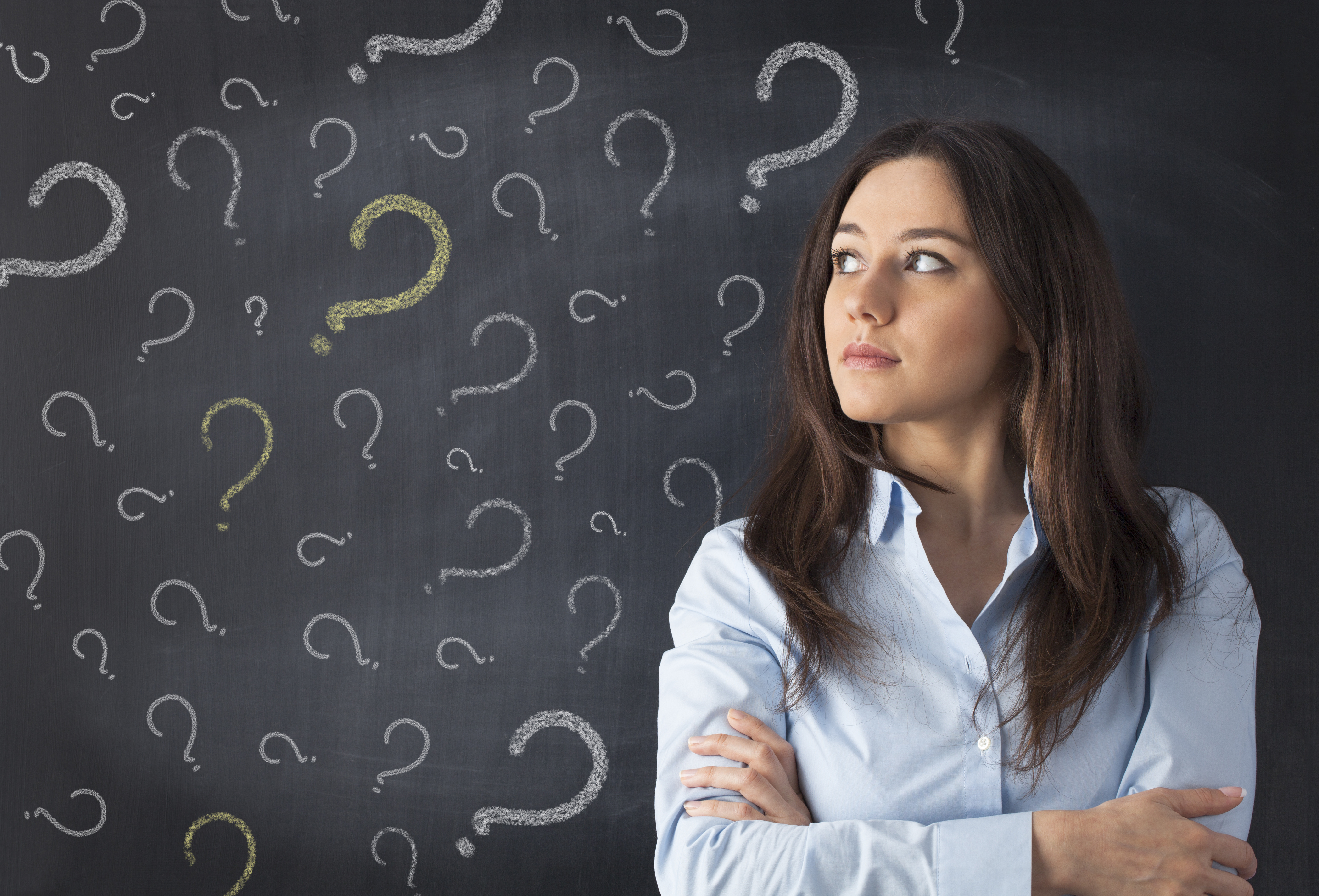 woman standing in front of a blackboard with lots of question marks on it