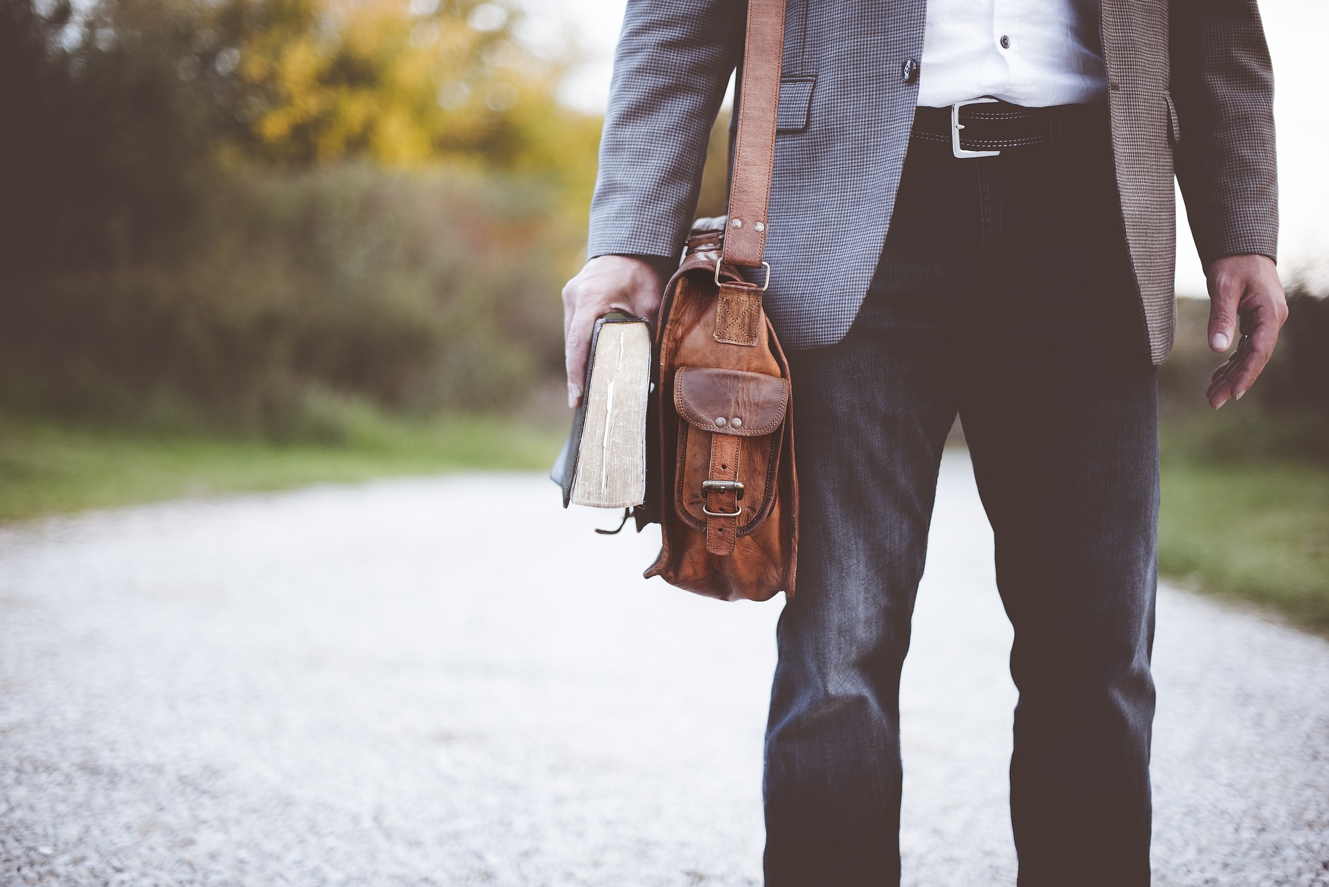 man with a jacket holding a book in his hand outdoors