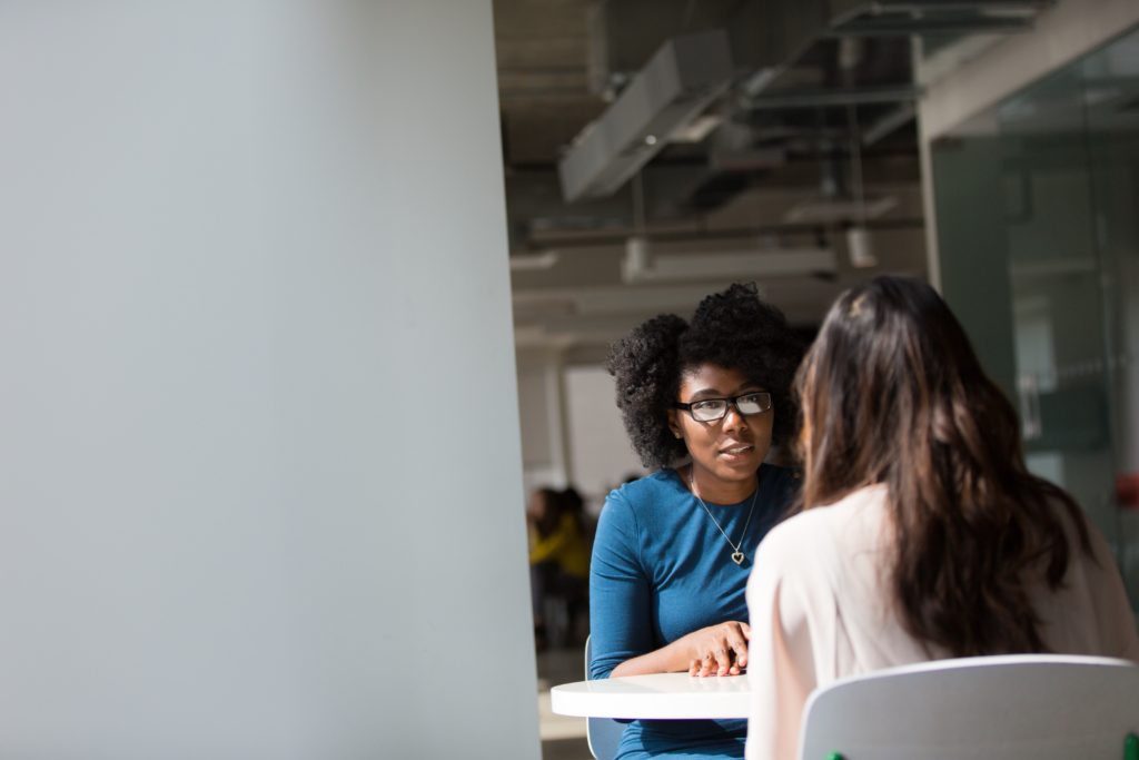 two women sitting at a university campus café and talking