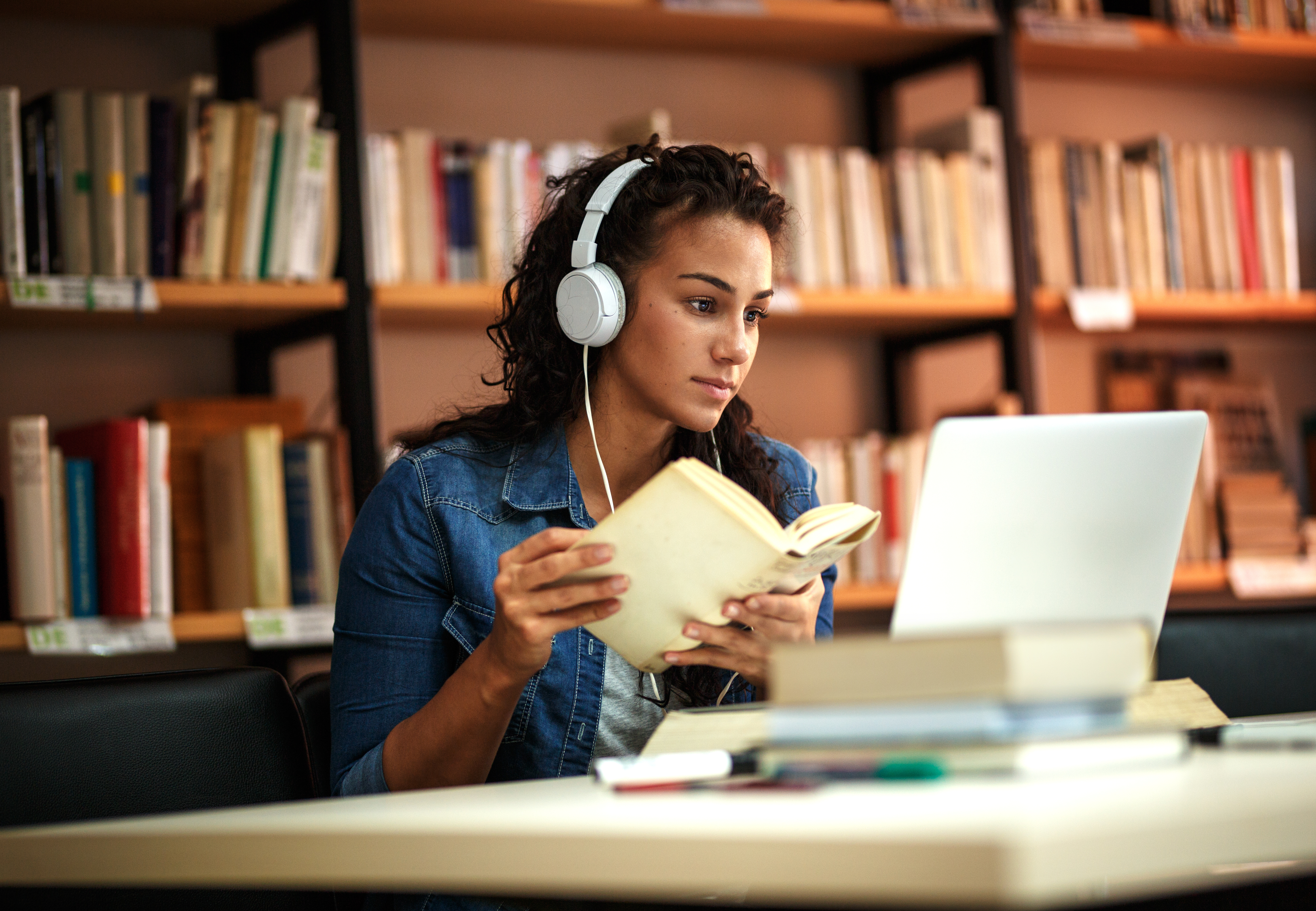 woman with headphones studying inside a library