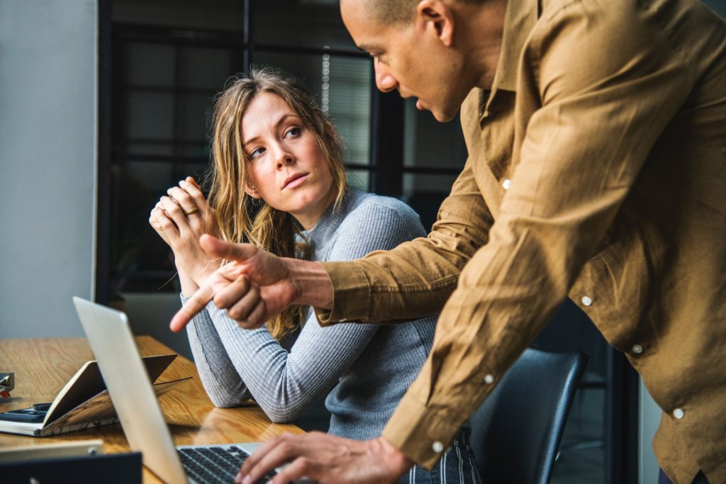 man explaining something on the laptop to his colleague