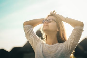 happy woman holding her hands up and enjoying the sunlight