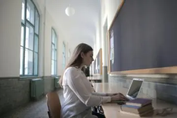 focused student working on her laptop in a library hallway