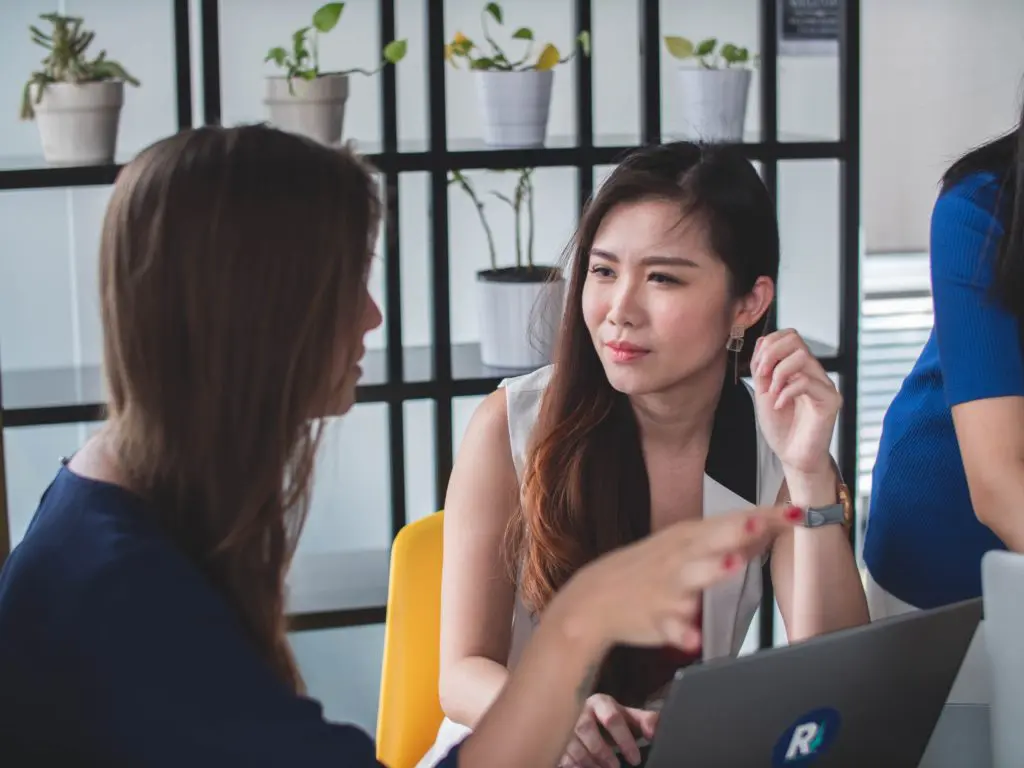 two women discussing details in front of laptop