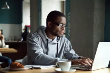 african american man studying on laptop inside a coffee shop