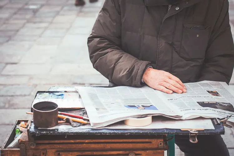 senior citizen reading a newspaper outside