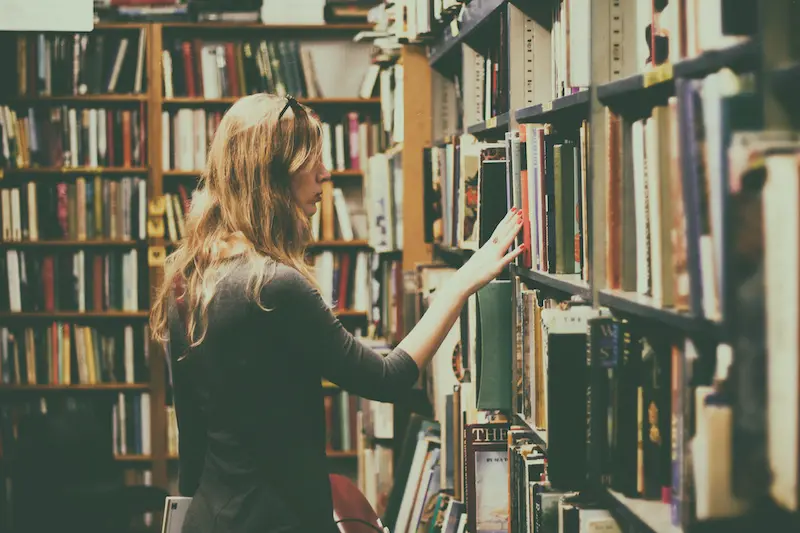 woman with blonde hair searching through a library