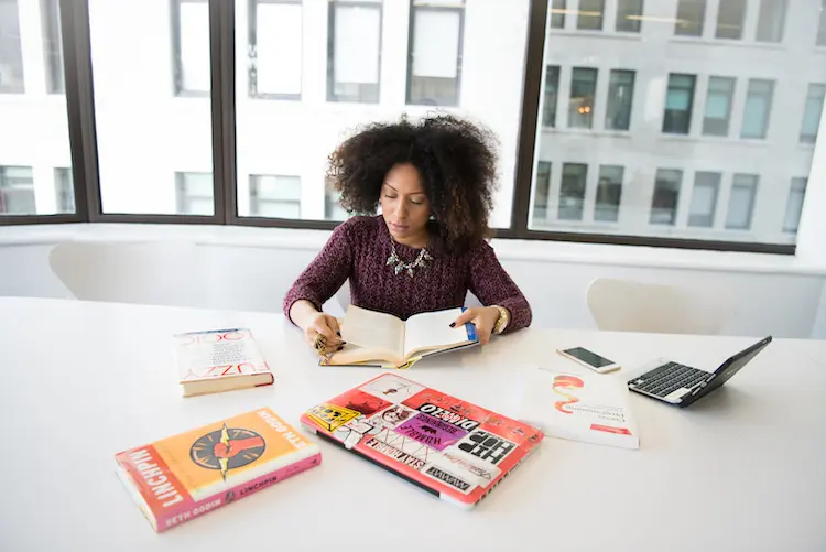 woman with afro hair reading a book in a conference room