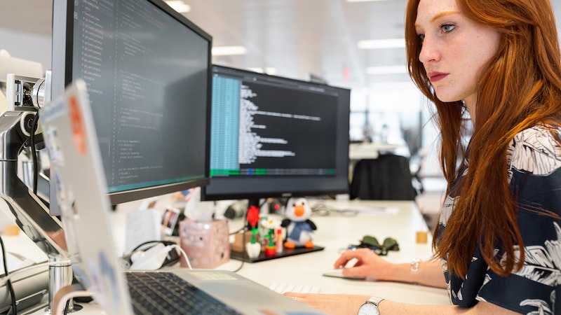 red haired woman in an office looking at her laptop