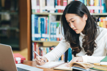 woman focused on taking notes in a library