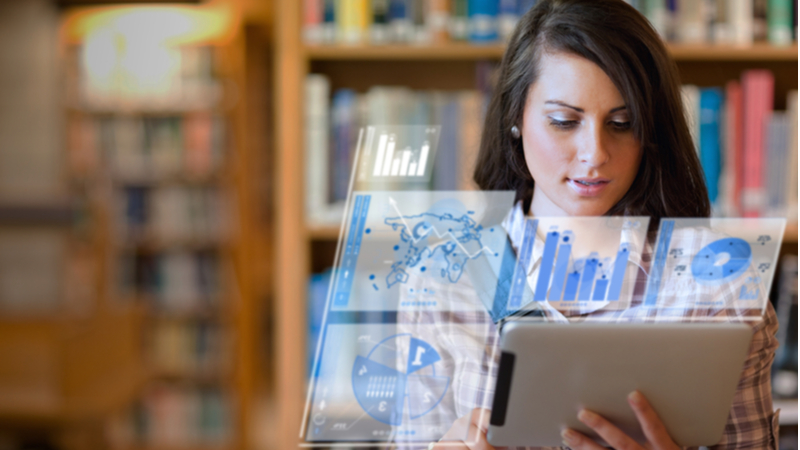 woman looking at a tablet with analytical overlays in a library