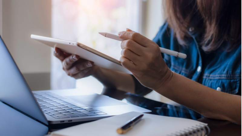 woman writing on a tablet computer