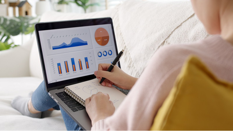 woman taking notes in front of laptop at home