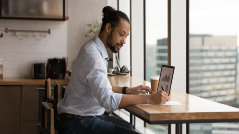 african american grad student working on his laptop from his home kitchen